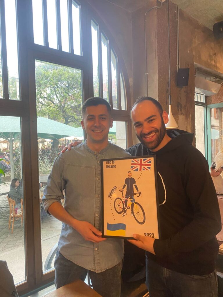 Tom and Volodymyr looking at the camera holding a poster.